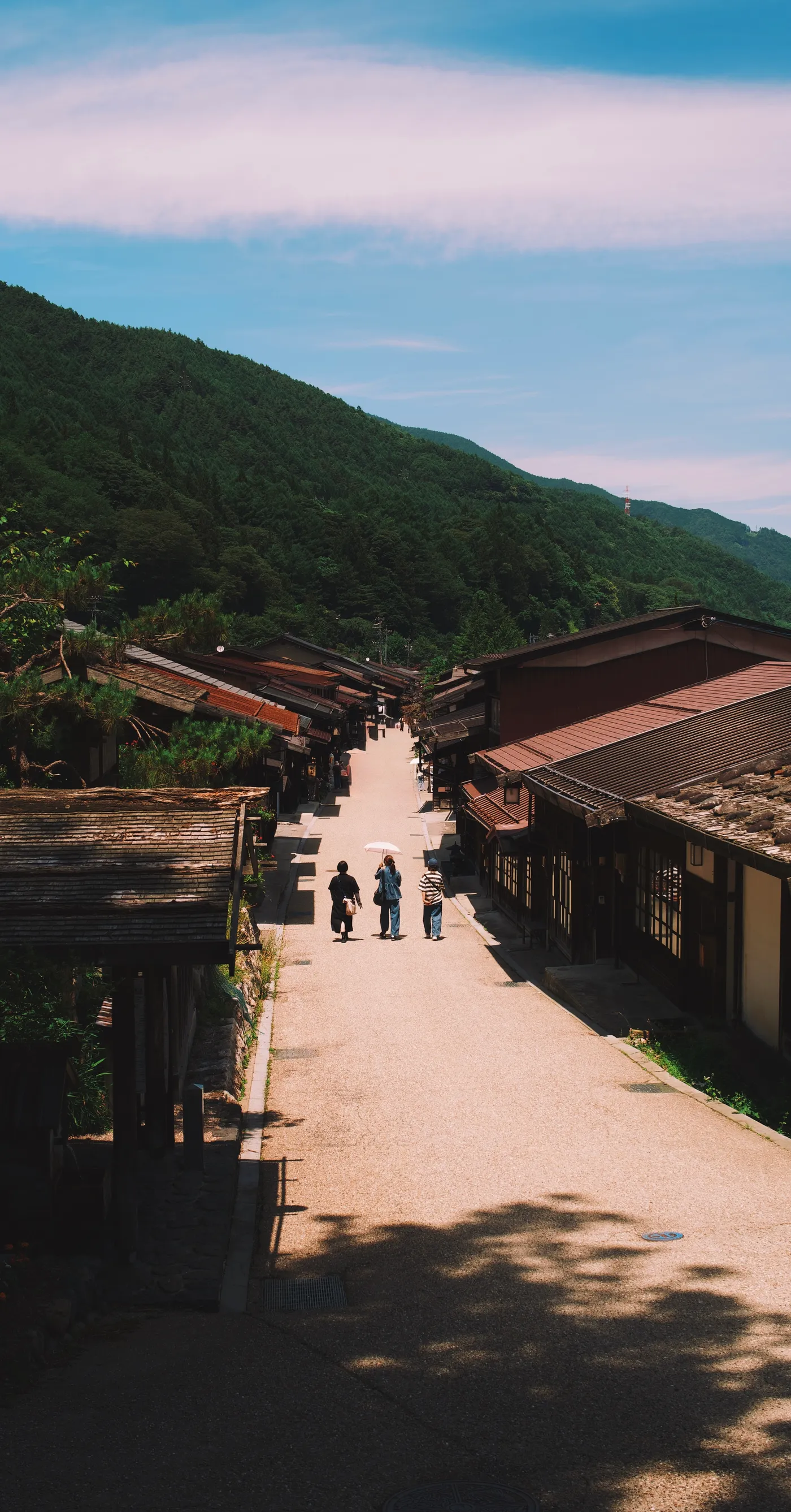 Two walkers seen from behind, receding into the distance along the main road of Narai post town