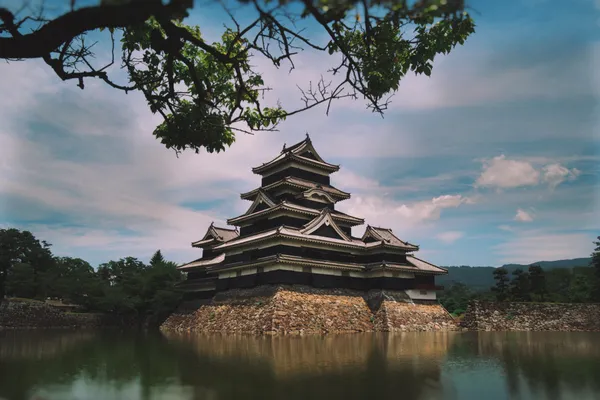 Matsumoto Castle rising from its moat, dramatic clouded sky