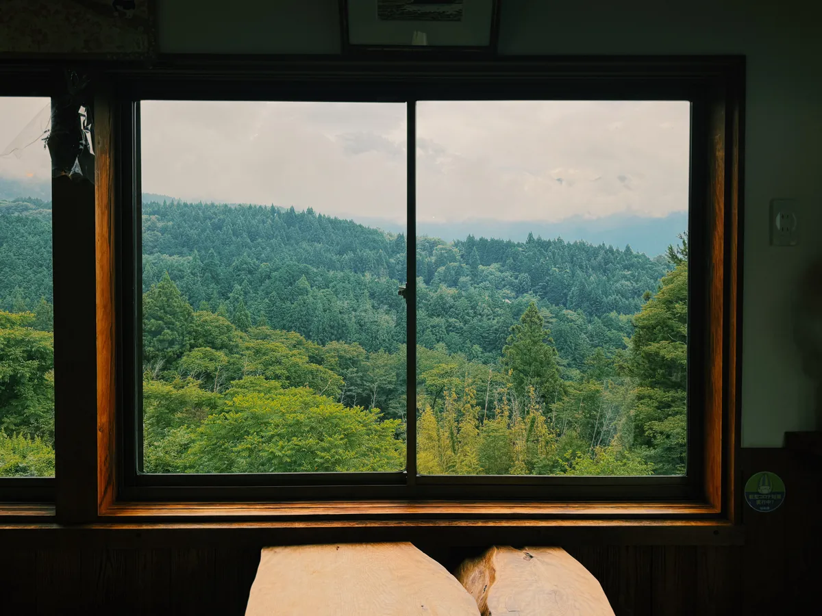 View east over the Kiso Valley from a wooden window frame high in Magome, forested hills receding into cloud