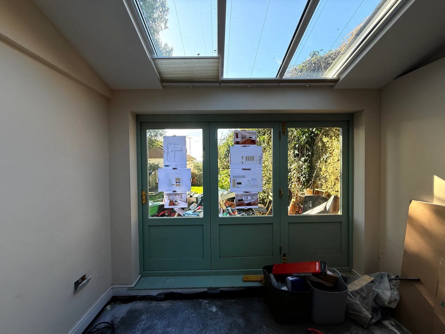 Kitchen plans pasted up on the windows of the doors out to the garden.