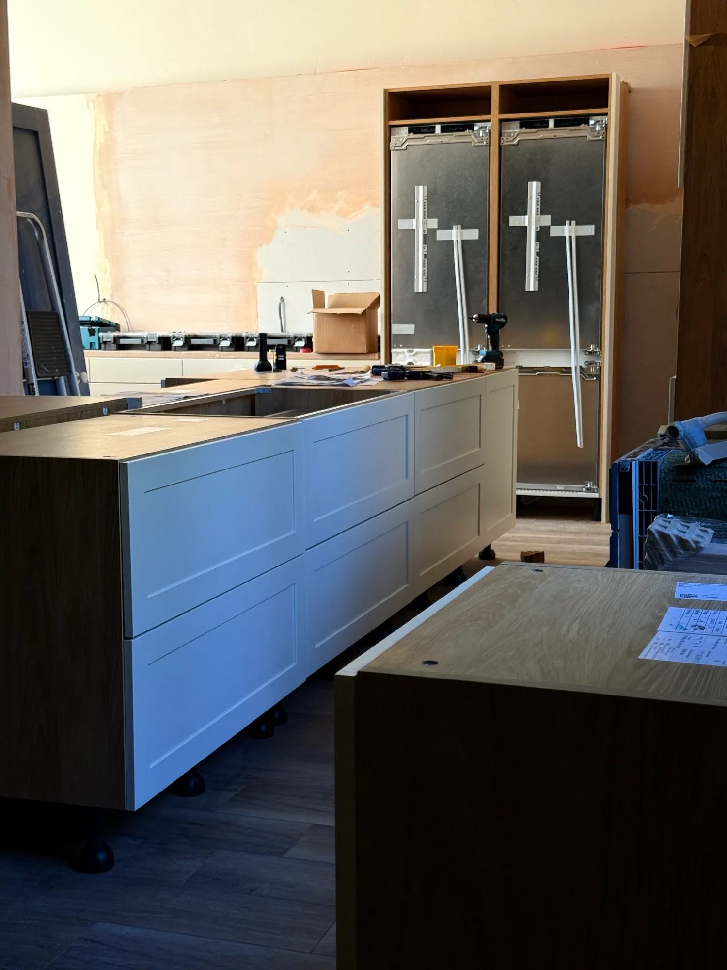 A view across the front of the kitchen island over to the end wall where the fridge freezers are now in the units.