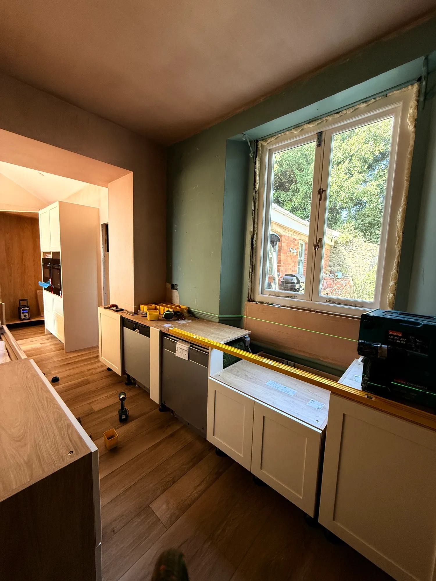 View looking into the kitchen along the rear wall with a set of cabinets where the sink and dishwashers are mid-install.