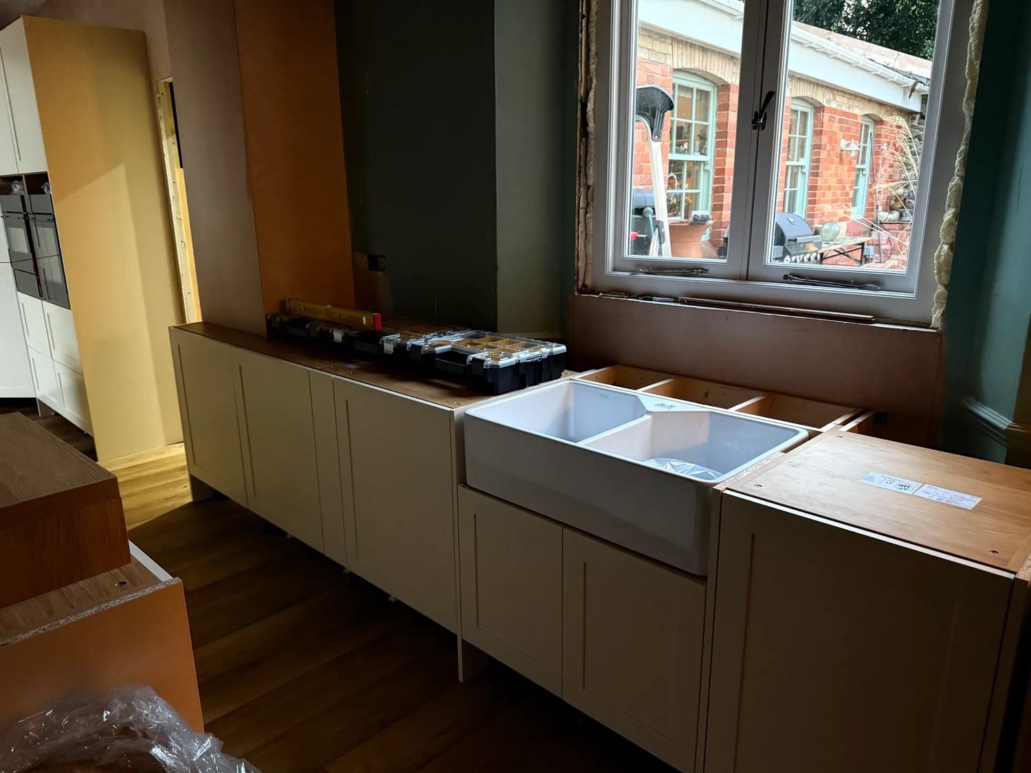 The run of cabinets under the window to the back garden with the dishwashers and sink units.