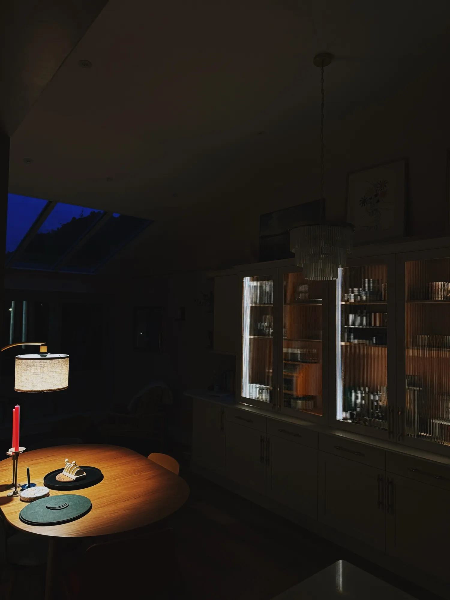 Night time view looking across the island into the dining area and the bar cabinets with the lights shining through the glass doors.