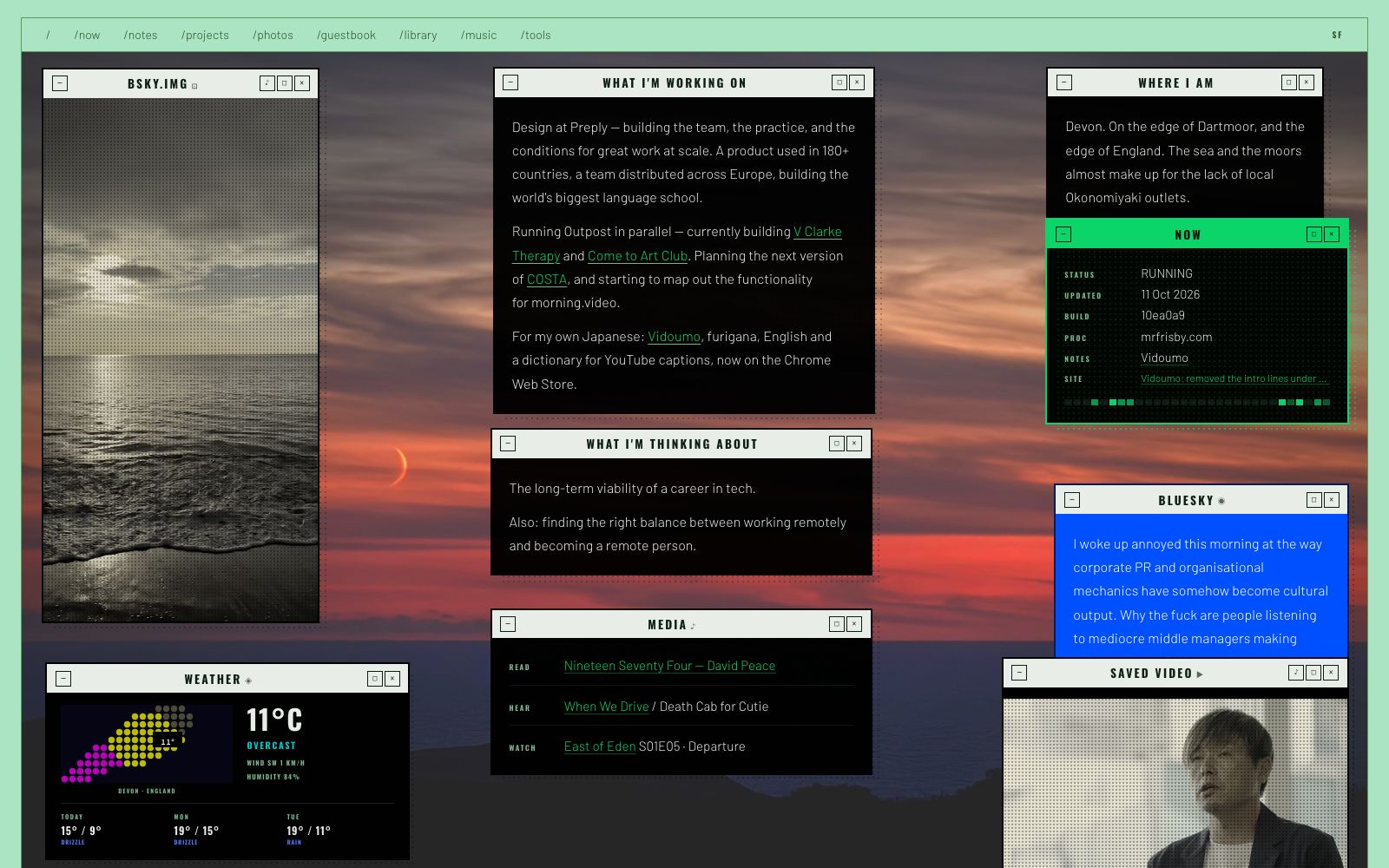 The now page: a desktop of black windows over a sunset, listing what I am working on, where I am, and what I am thinking about, with weather and a Bluesky post.